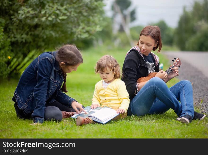 Little girl learning read and playing musical instruments outdoors, early all-round development.