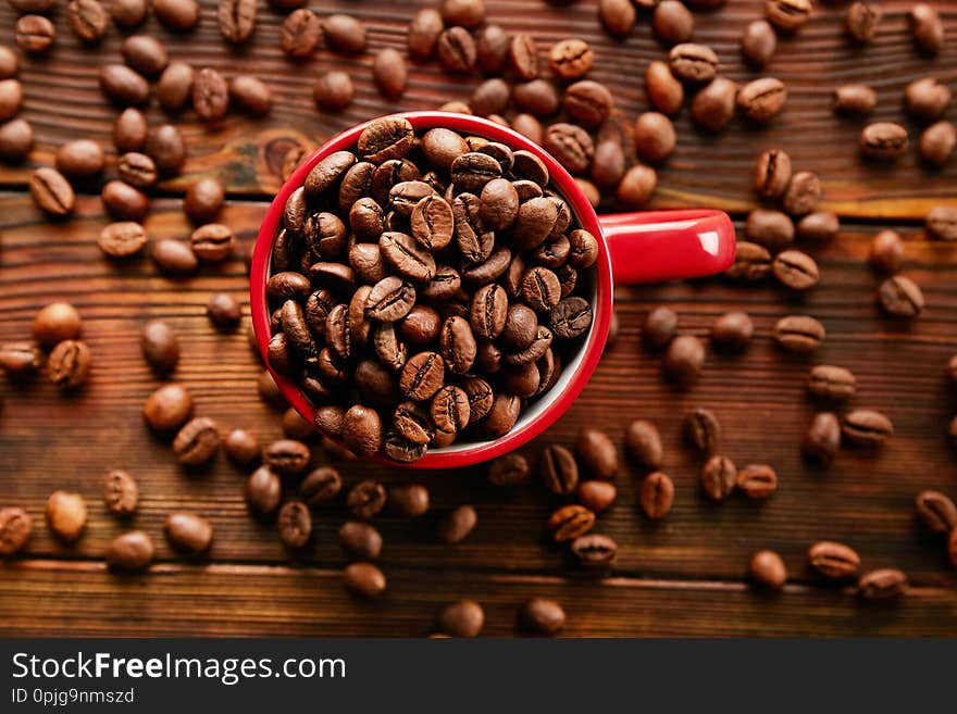 Coffee cup with roasted brown beans scattered on white table with a lot copy space for text. Flat lay composition. Close up, top view, background. Coffee cup with roasted brown beans scattered on white table with a lot copy space for text. Flat lay composition. Close up, top view, background