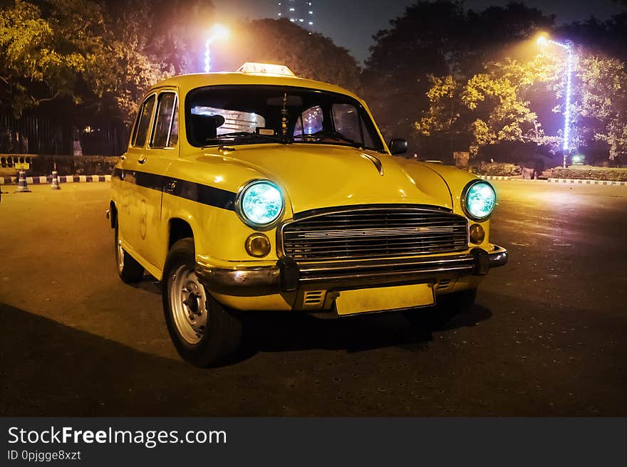 A yellow taxi model 50s-60s. Old retro car in the form of a city taxi on the night street of Kolkata. India. A yellow taxi model 50s-60s. Old retro car in the form of a city taxi on the night street of Kolkata. India