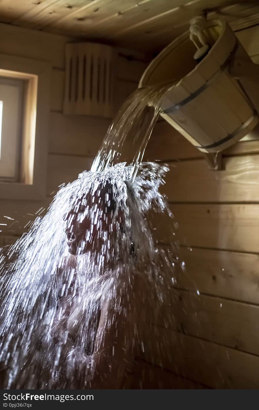 A Woman In A Russian Bath Or Sauna Is Poured With Cold Water From A Wooden Bucket, For Hardening And A Healthy Lifestyle, With