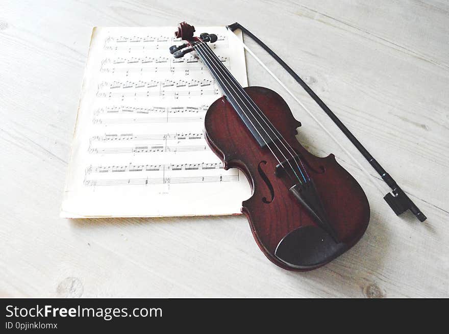 Small wooden violin and musical notes. Layed on wooden floor. Small wooden violin and musical notes. Layed on wooden floor.