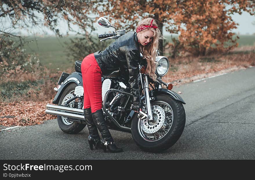 Young beautiful caucasian woman posing with motorcycle on the road. Young beautiful caucasian woman posing with motorcycle on the road.
