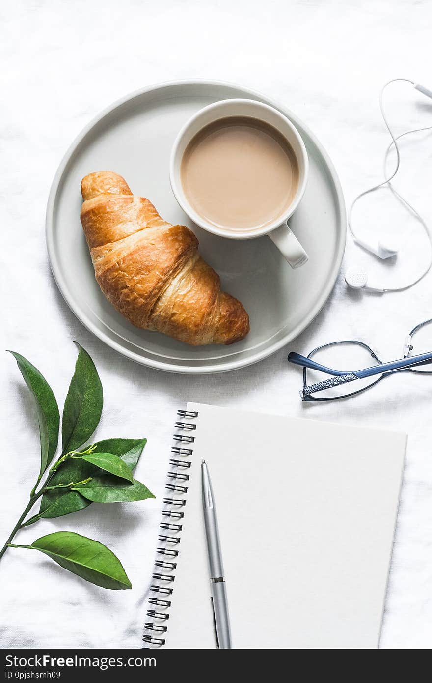 Morning plan. Coffee, croissant and  clean empty notebook on a light background, top view. Flat lay, copy space