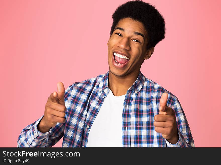 Excited guy pointing fingers at camera over pink background