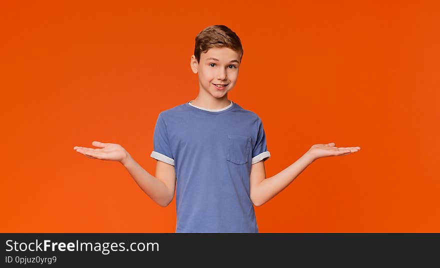 Cute little boy with doubting expression, both palms facing up, orange background with empty space. Cute little boy with doubting expression, both palms facing up, orange background with empty space