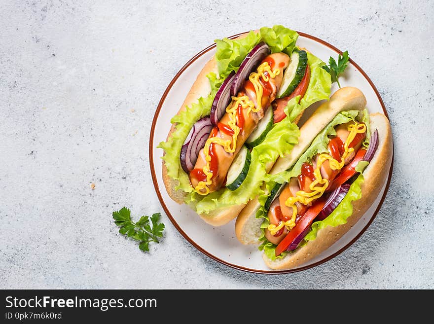 Hot dog with fresh vegetables in white plate on white table. Top view with copy space. Hot dog with fresh vegetables in white plate on white table. Top view with copy space.