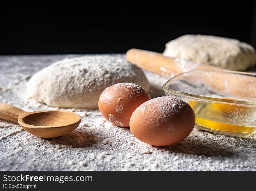 White flour with eggs, butter and dough on a cooking board, product