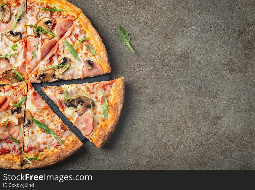 Italian fast food. Delicious hot pizza with ham and champignons sliced and served on brown concrete table, close up view. Menu photo. Top view with copy space. Flat lay