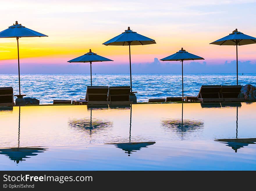 Umbrella and chair around swimming pool in resort hotel for leisure travel and vacation