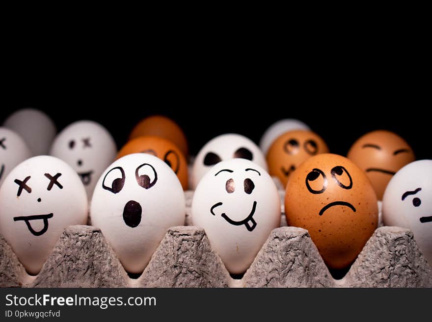 Eggs with funny expressions simulating human faces on a black background to write. Concept of ethnic diversity and moods. Eggs with funny expressions simulating human faces on a black background to write. Concept of ethnic diversity and moods