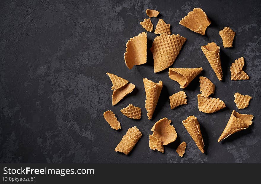 Crushed waffle ice cream cones on a black background, top view with copy space scoops summer dessert delicious sweet cold flavor tasty fresh sundae frozen snack dairy refreshment wafer empty calorie cool yummy colorful concept wooden cornet overhead gelato variety milk confection refreshing crisp thirst unhealthy