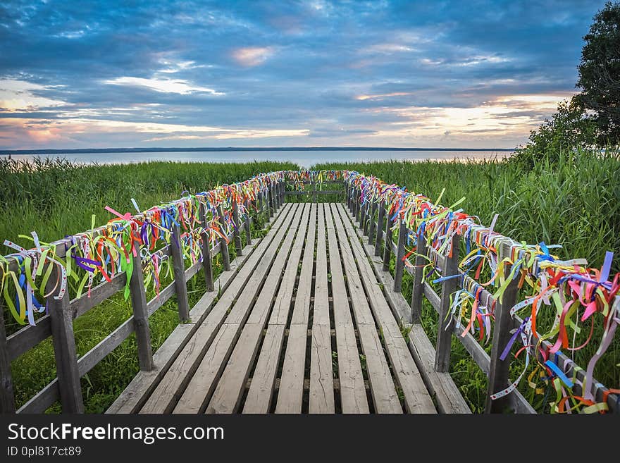 Bridge on the lake with colorful ribbons, bridge at sunset, colorful ribbons on the railing of the bridge