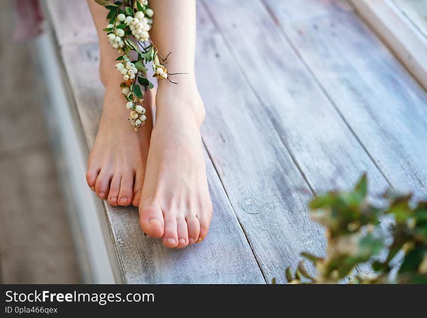 Beautiful women`s feet with flowers on wooden background, foot skin care