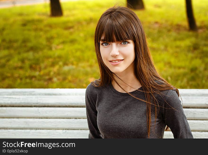 Portrait of a young woman sitting in the Park on a bench