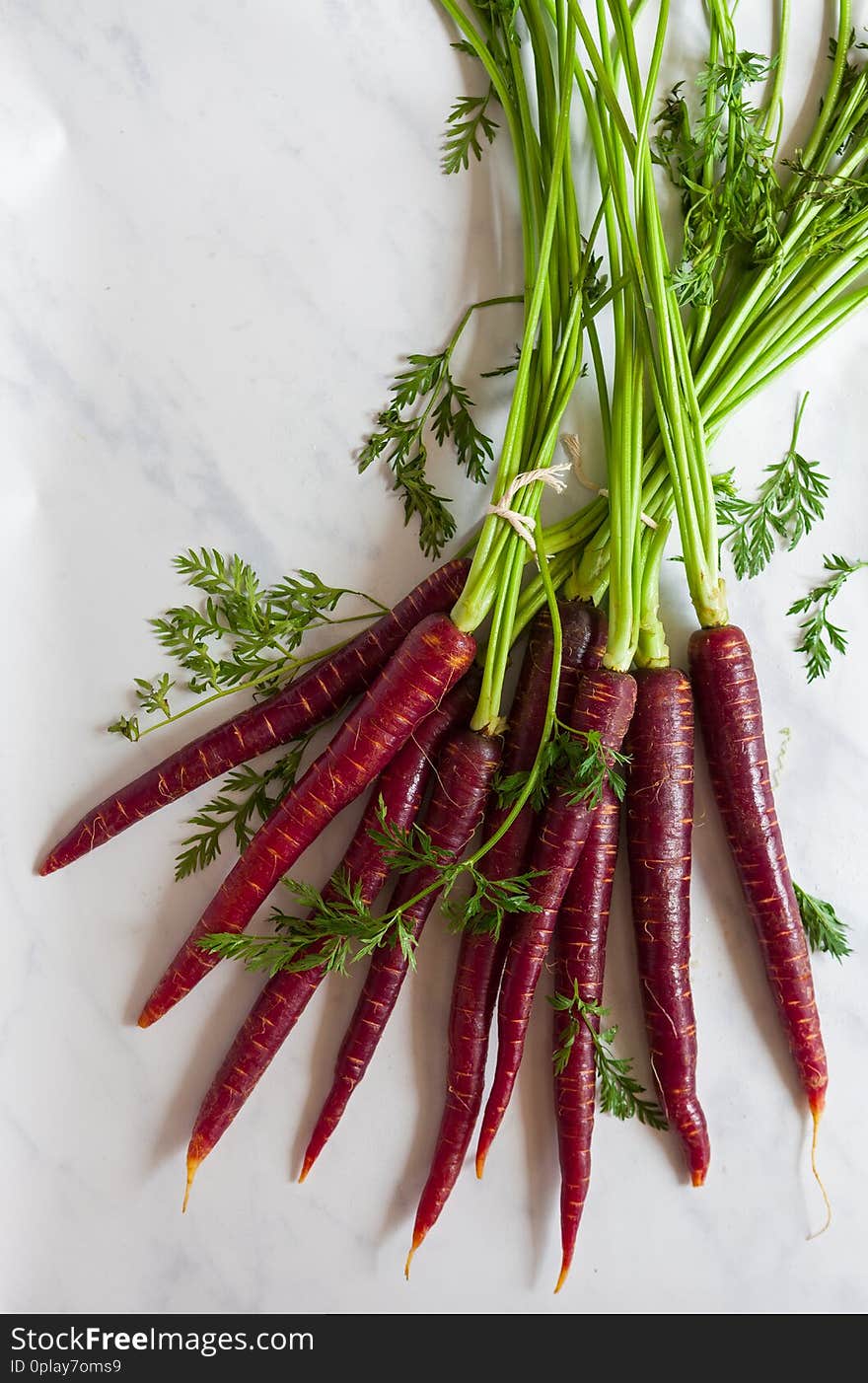 Overhead view of a fresh, organic bunche of purple carrots on a marble surface. Overhead view of a fresh, organic bunche of purple carrots on a marble surface