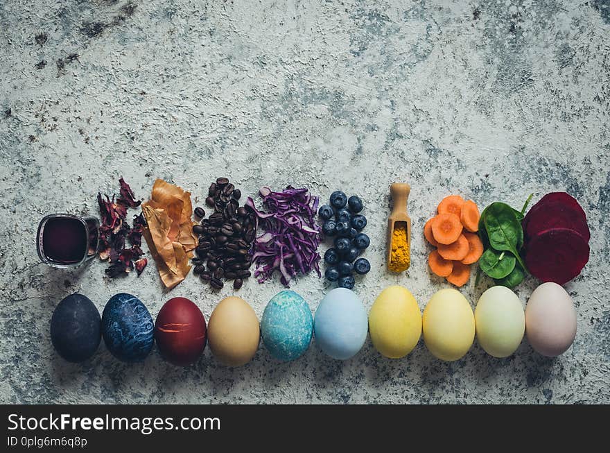 Easter eggs painted with natural egg dye from fruits and vegetables. Homemade naturally dyed Easter eggs with ingredients on concrete background. Copy space. Top view