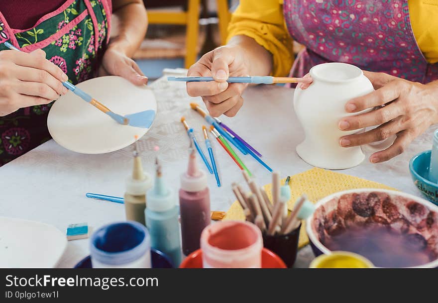 Woman coloring handmade dishes using brush and color