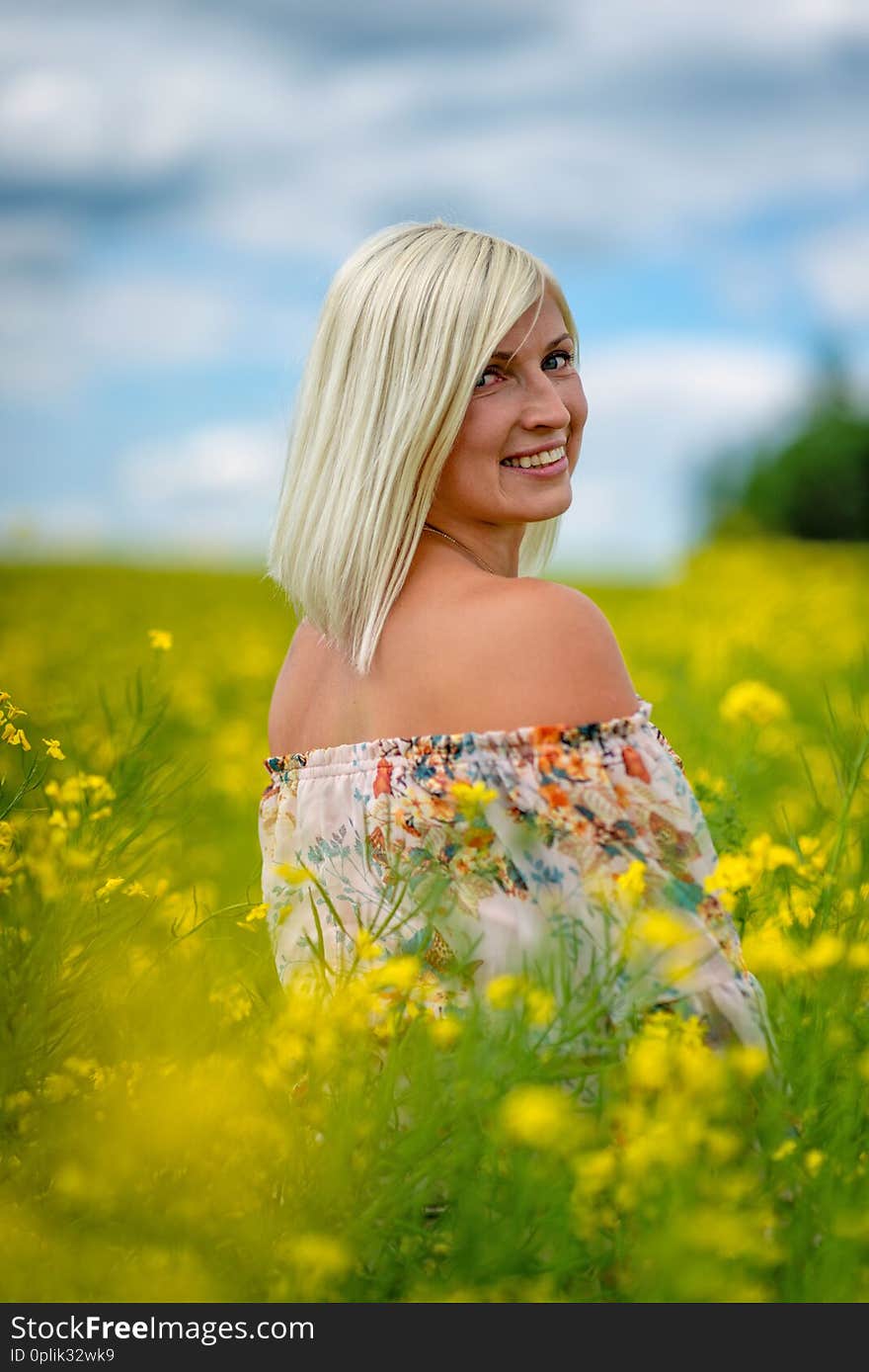 Soft, selective focus. Beautiful, attractive, blond woman in a yellow flower meadow