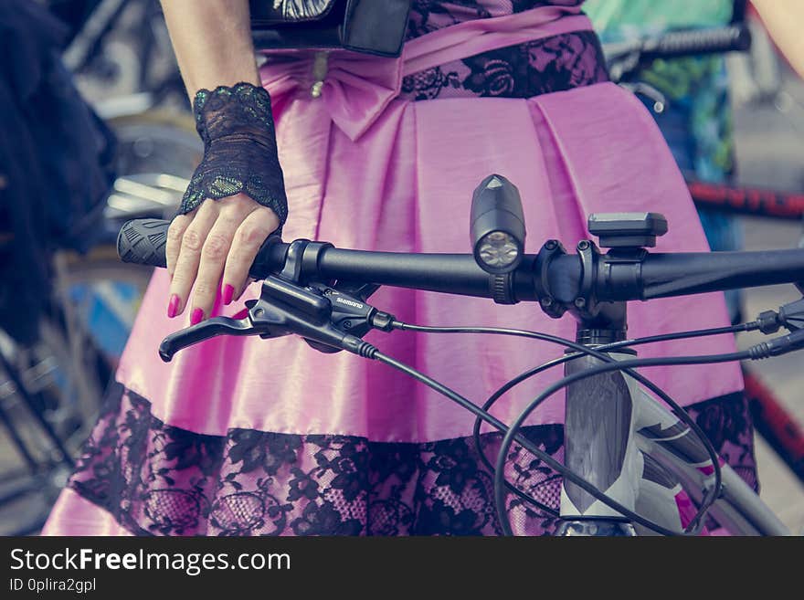 Concept: women on bicycles. Hands holding the handlebars. Pink skirt with black lace.