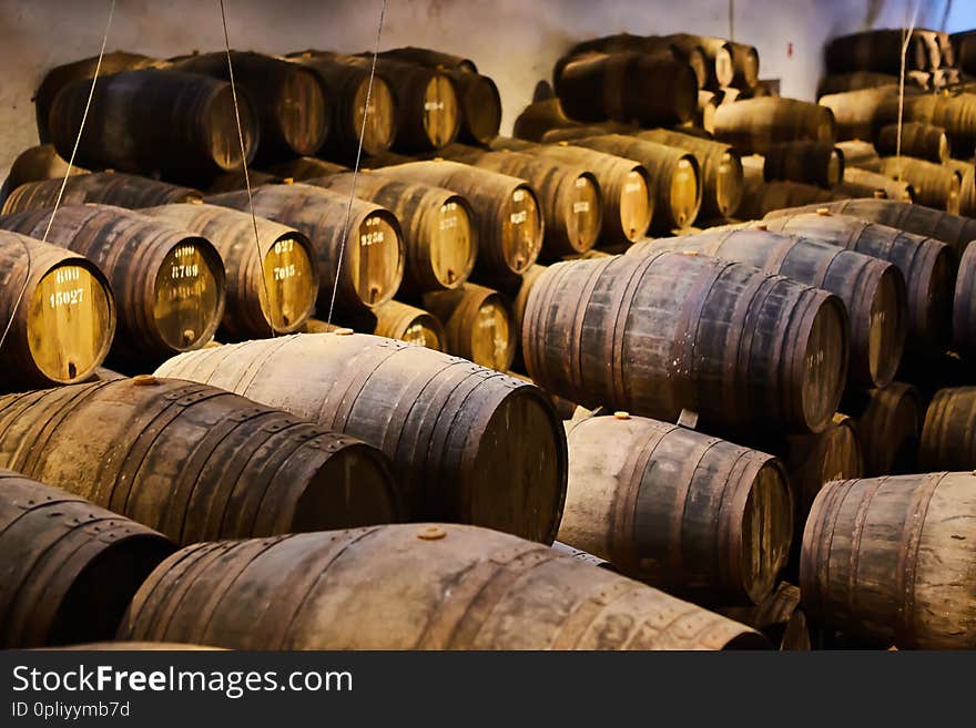 Old aged traditional wooden barrels with wine in a vault lined up in cool and dark cellar in Italy , Porto, Portugal, France