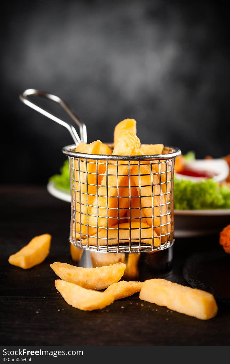 French fries in a metal holder on dark background. French fries in a metal holder on dark background