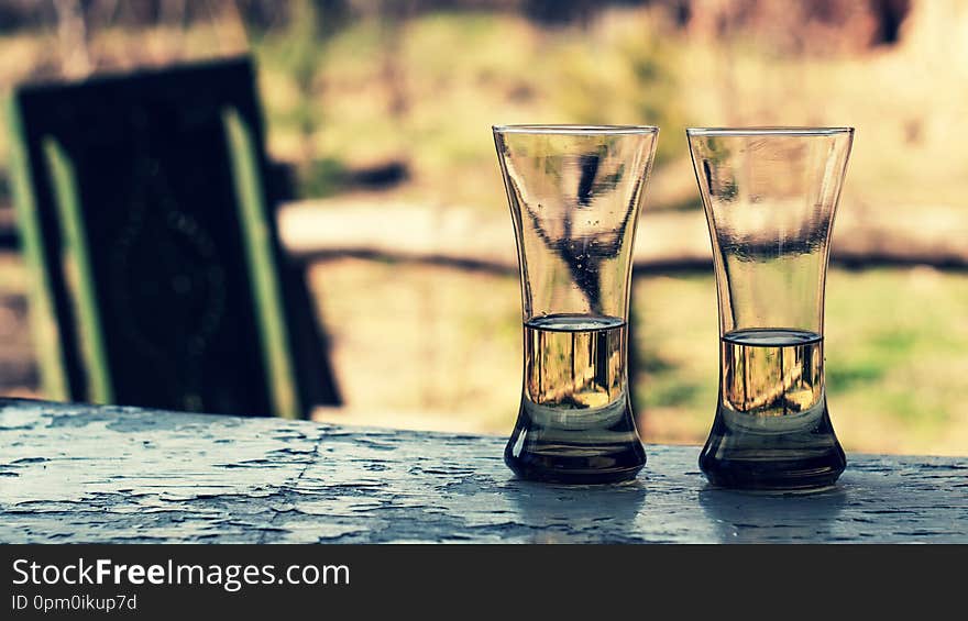 Two glasses with wine or juice on a wooden table in the garden