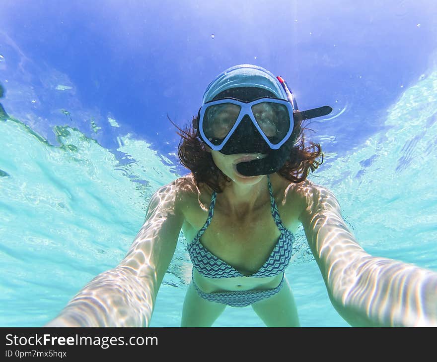 woman taking an underwater selfie while snorkeling in crystal clear tropical water