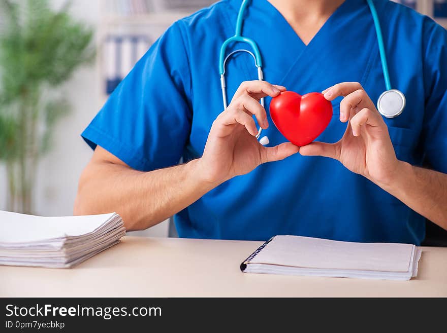 The male doctor cardiologist holding heart model