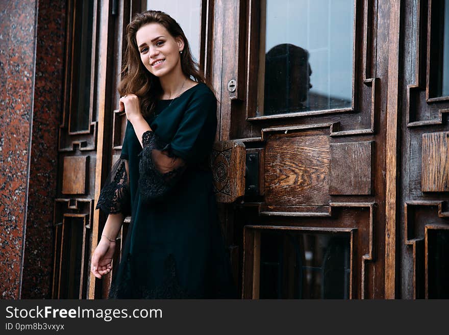 Young girl in green dress near old big building door.