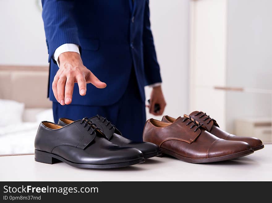 The young handsome businessman choosing shoes at home