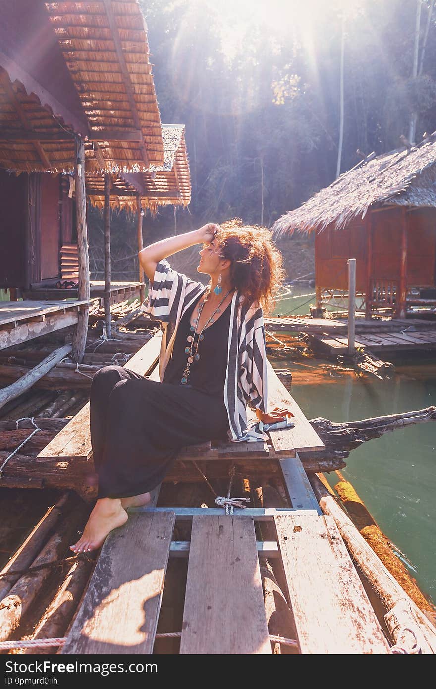 Beautiful young stylish boho woman at wooden floating village