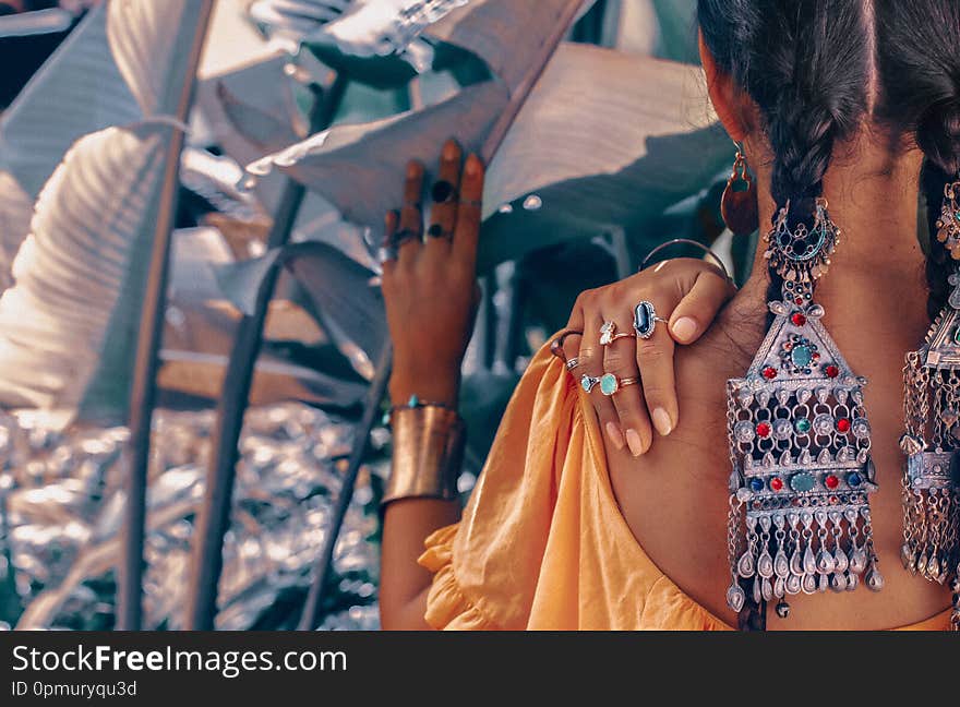 Close up of beautiful young fashionable woman with stylish boho accessories posing on natural tropical background