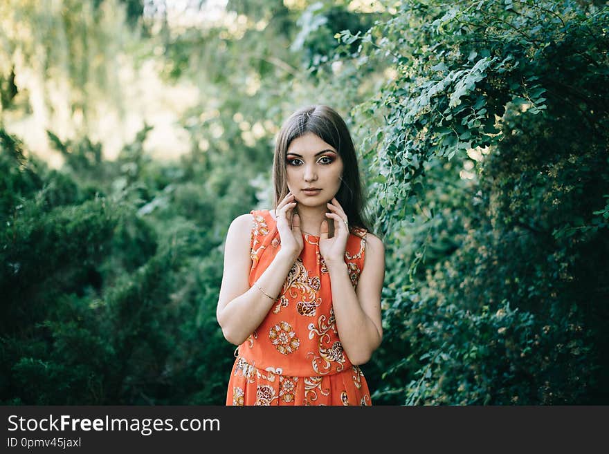 Beautiful young girl in a summer red dress in a park