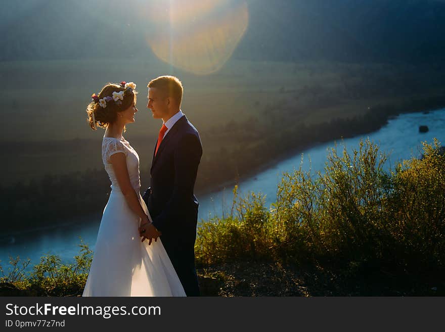 Happy wedding couple staying and kissing over the beautiful landscape with mountains. Altai, Siberia. Happy wedding couple staying and kissing over the beautiful landscape with mountains. Altai, Siberia