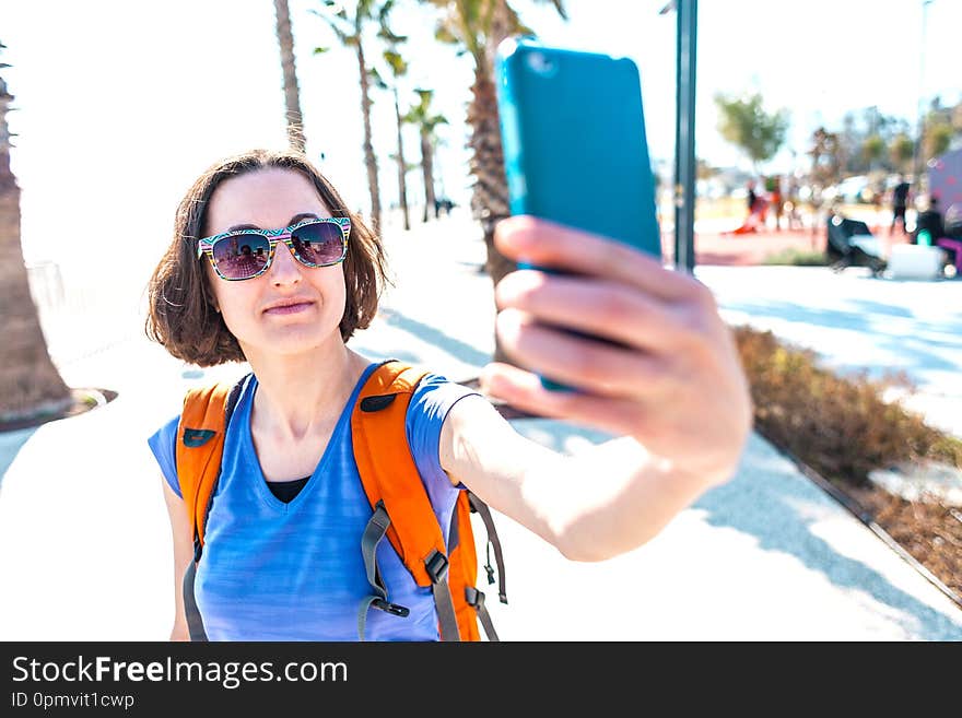 A girl takes a selfie on the waterfront. A woman walks through the resort town and takes pictures. Brunette travels around the Turkish city