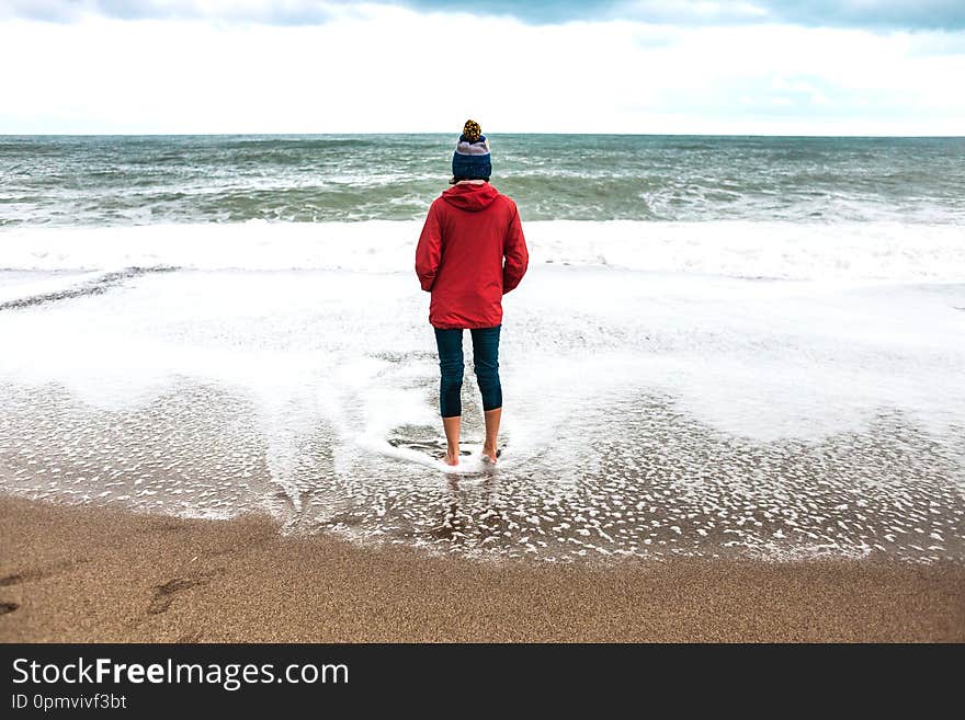 Barefoot woman looks at the winter sea