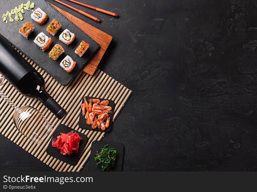 Set of sushi and maki with a bottle of wine on stone table. Top view with copy space