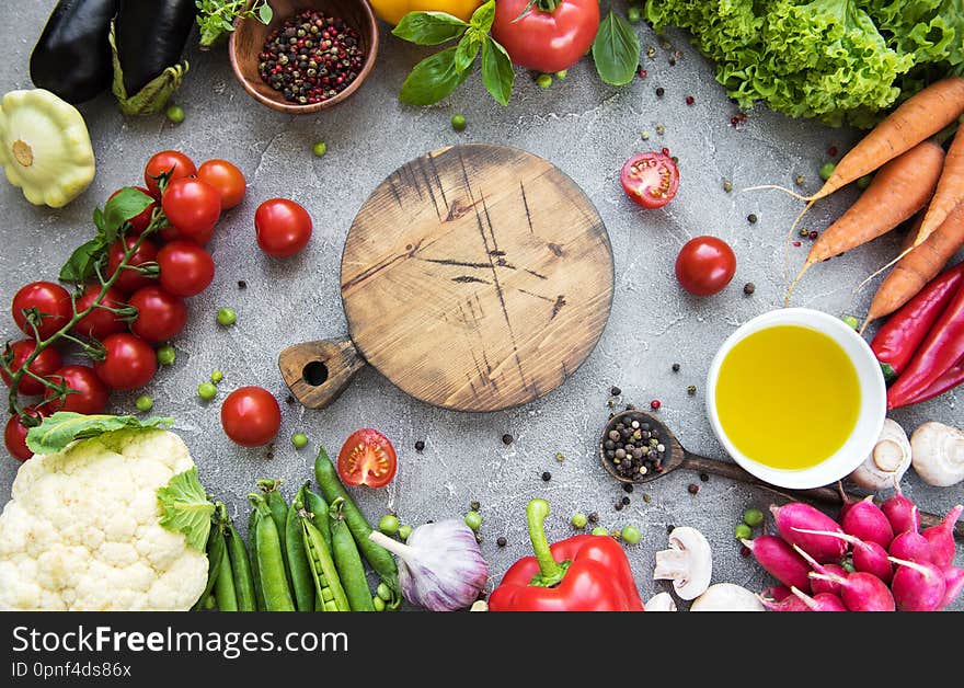 Empty board and fresh vegetables on a concrete background