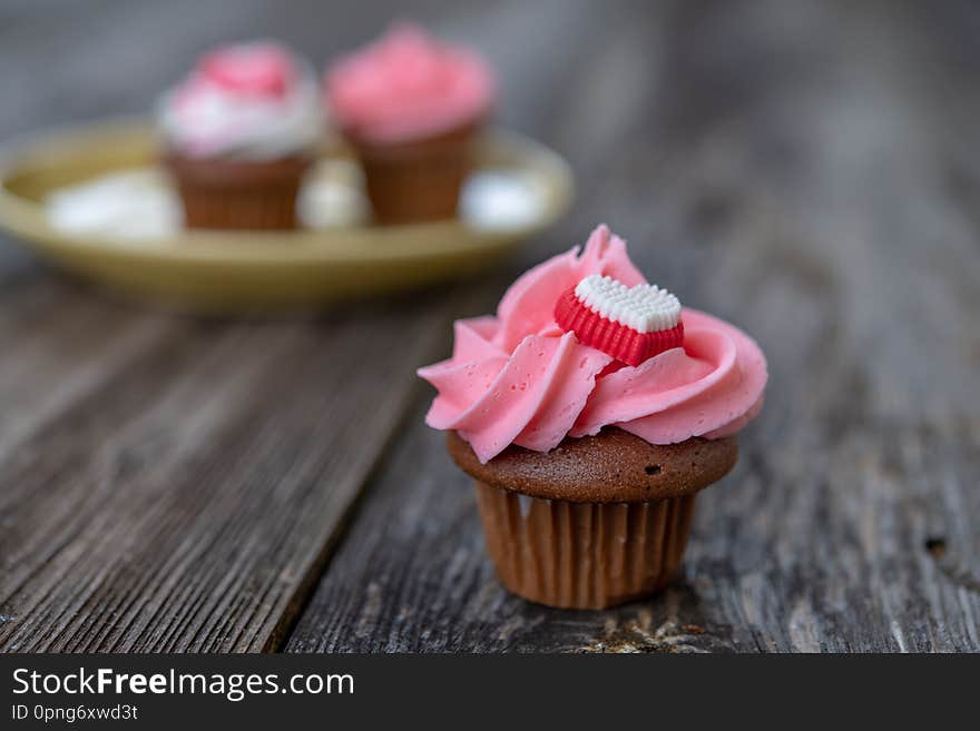 Pink and white muffins with heart on wooden ground