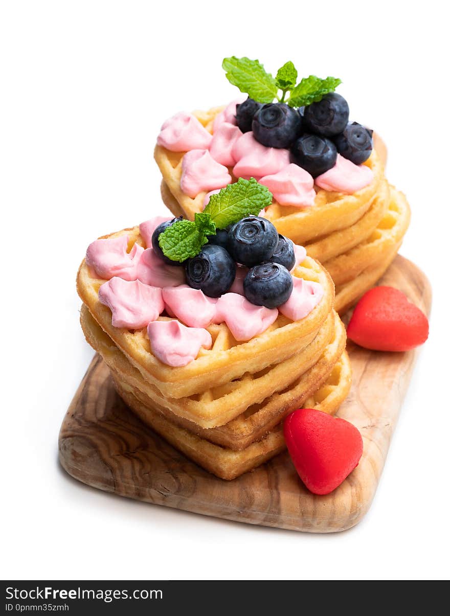 Stack  of heart shaped waffles with pink cream and blueberry isolatedon white