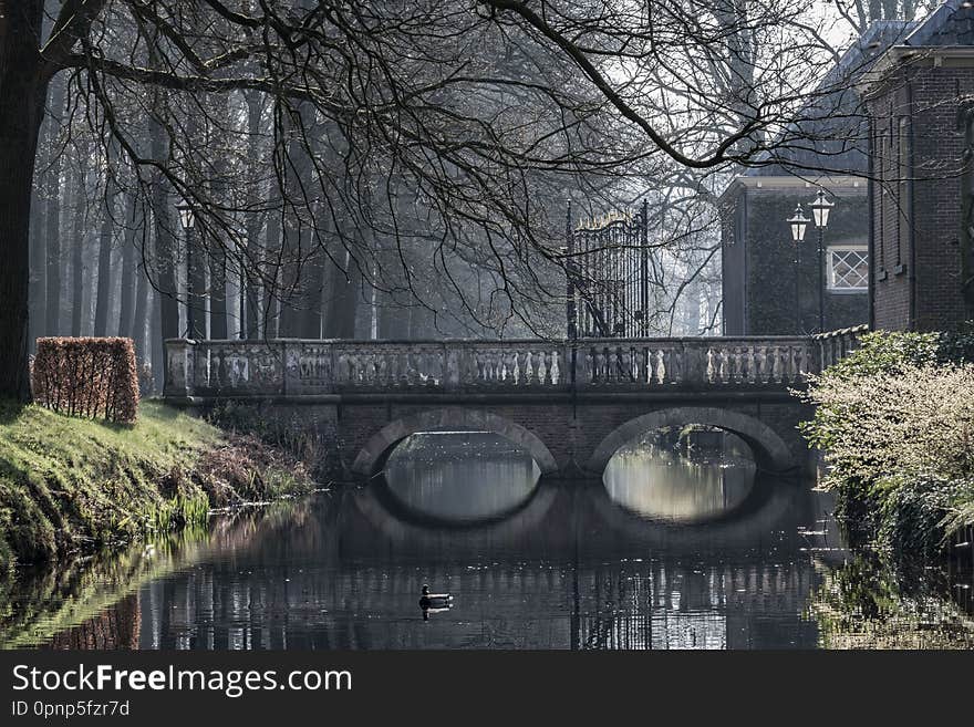 Mysterious bridge reflected in water on a foggy morning  in Laren in Netherlands