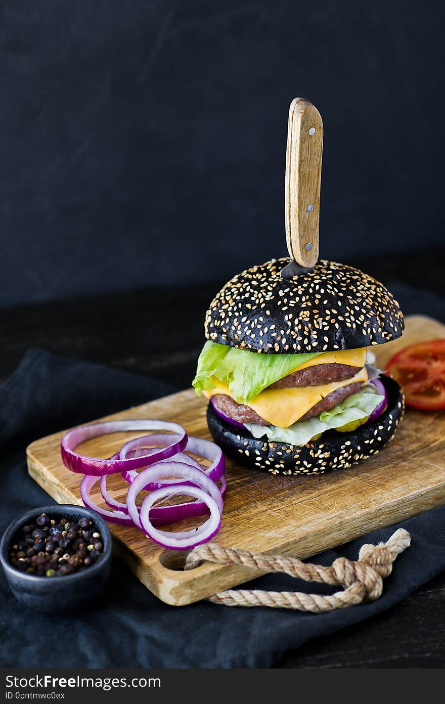 Juicy double cheeseburger. Side view, black background, space for text.