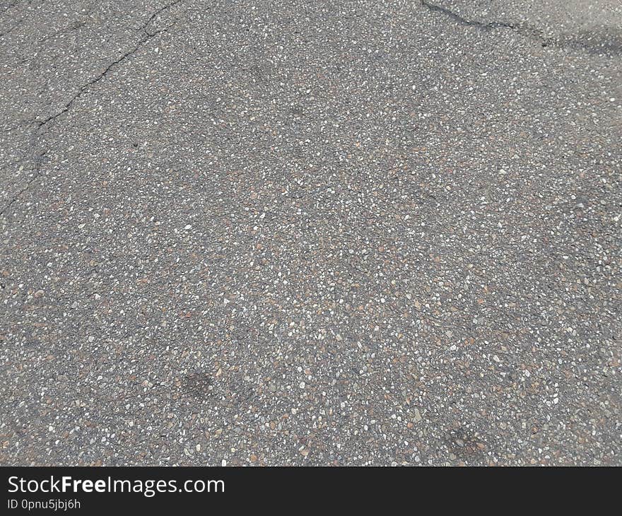 An old, worn asphalt pathway with multiple fractures on the surface. An old, worn asphalt pathway with multiple fractures on the surface.