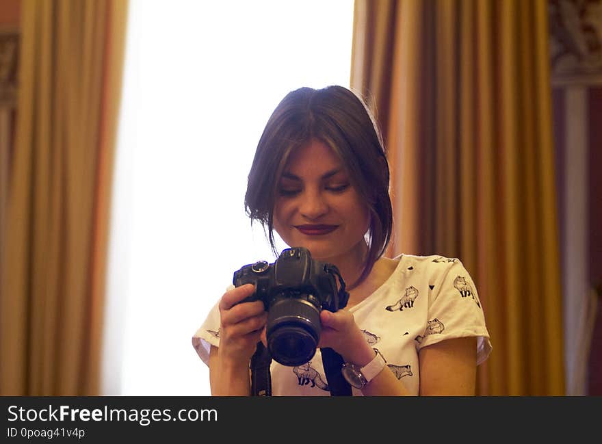 A beautiful girl smiling looks at photos on a small screen on the camera.Photo studio. A beautiful girl smiling looks at photos on a small screen on the camera.Photo studio.