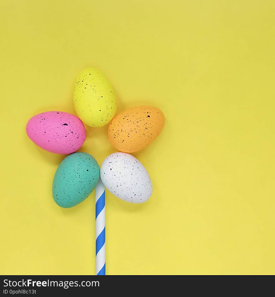 Flower made from Easter eggs, flat lay style against a bright yellow background with copy space. Easter concept.