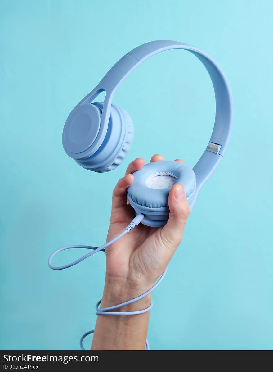 Hand wrapped cable holds headphones on blue background