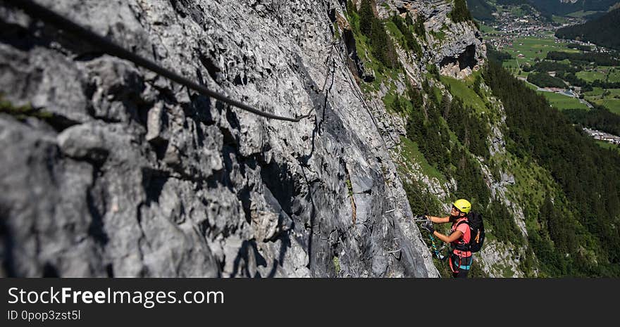 Pretty, female climber on a via ferrata - climbing on a rock in Swiss Alps