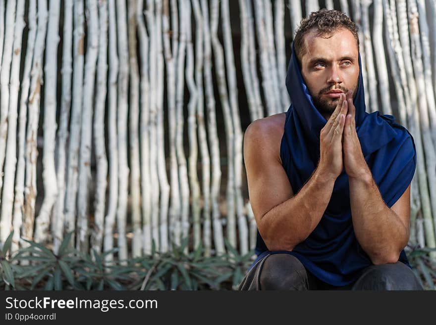 Fashion guy makes namaste near bamboo white background, prays.