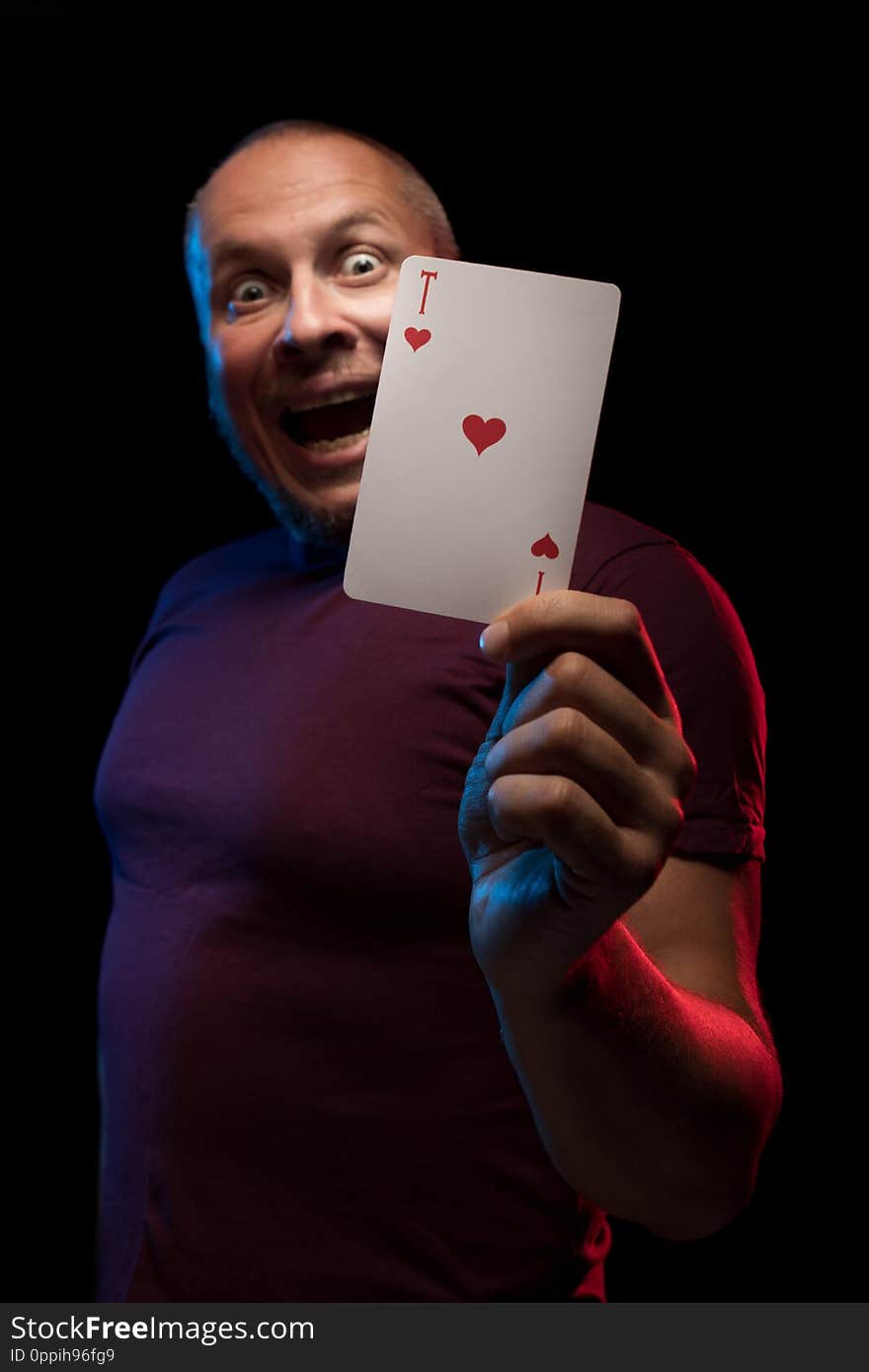 A man holds a deck of play cards and shows tricks in a scenic light.