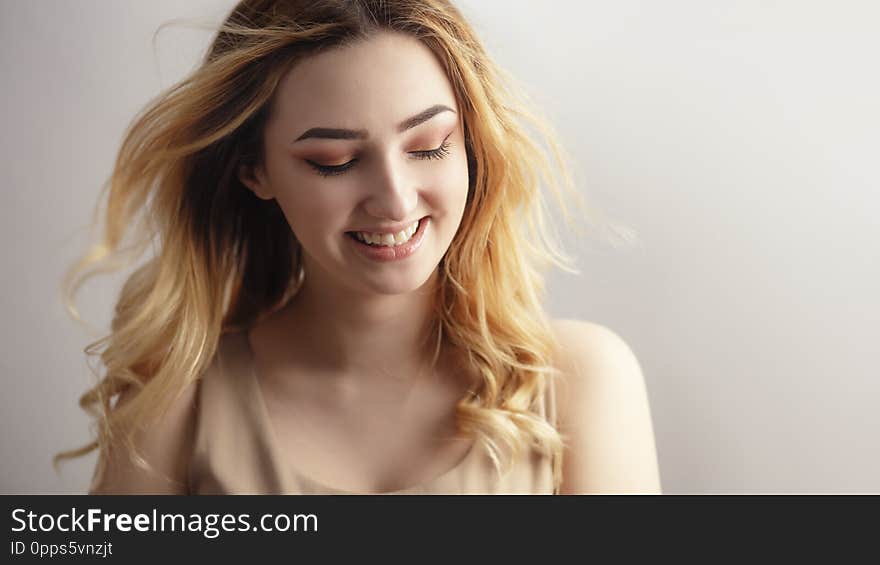 Studio portrait of a beautiful sincerely laughing girl, young woman face with curly hair disheveled from wind , the concept of